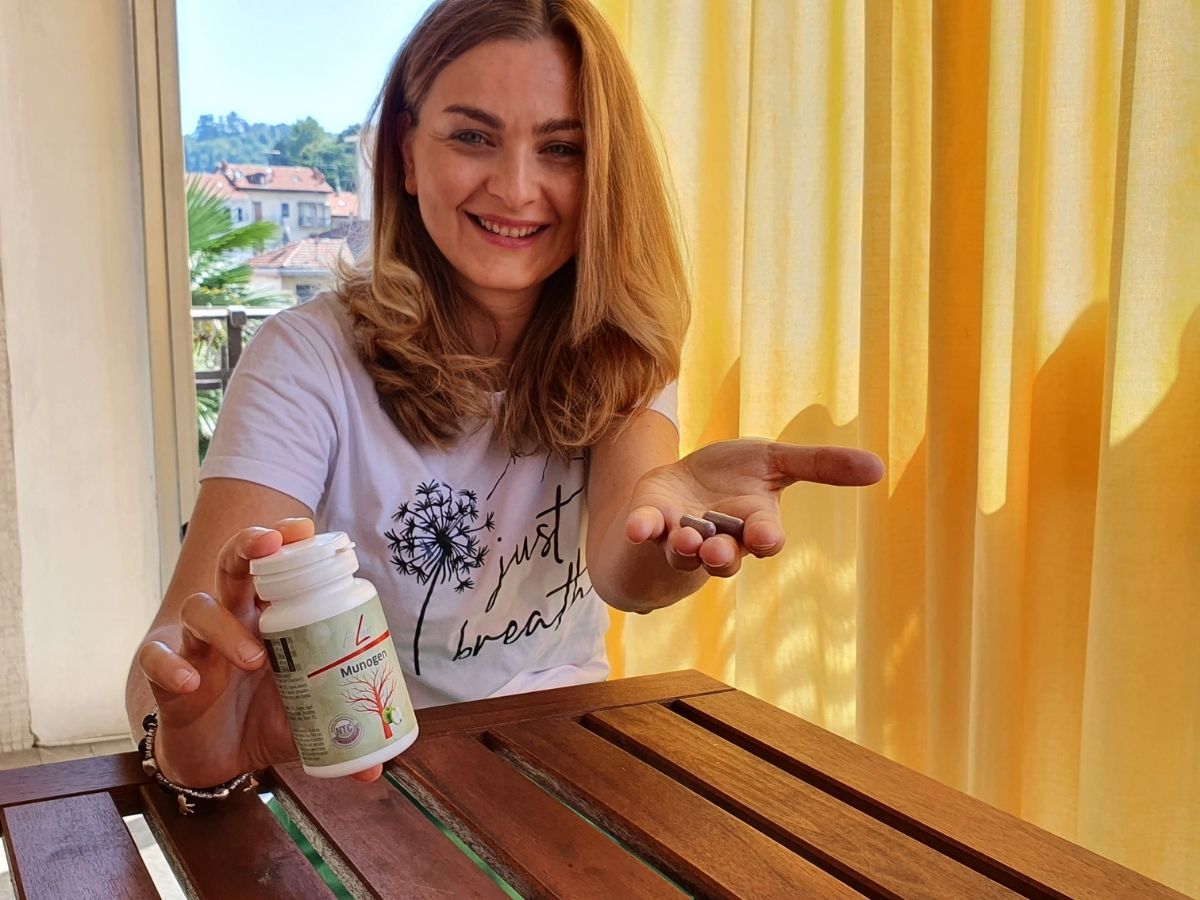 Munogen FitLine: Simonetta in veranda con barattolo in mano e 2 capsule nell'altra mano, prima di assumere Munogen